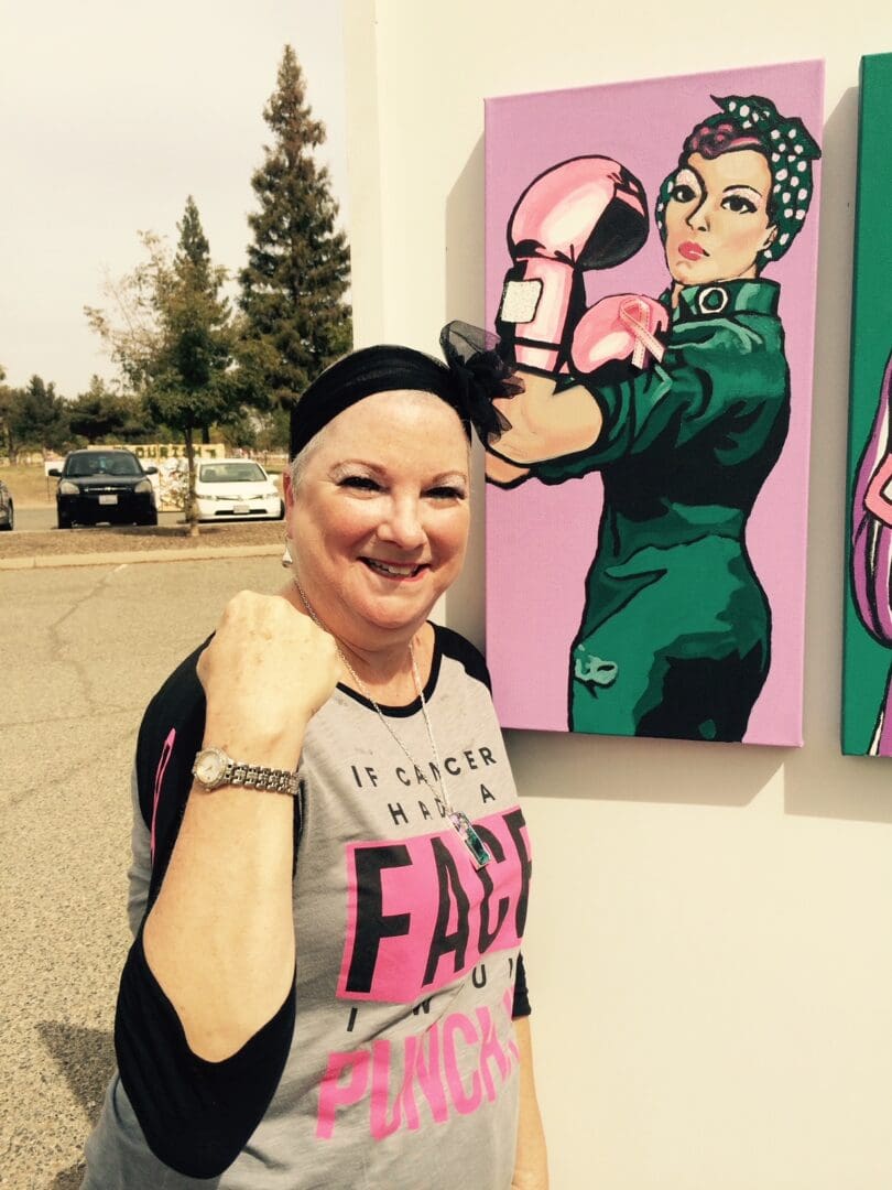 A woman with a black headband and pink shirt standing in front of two paintings.