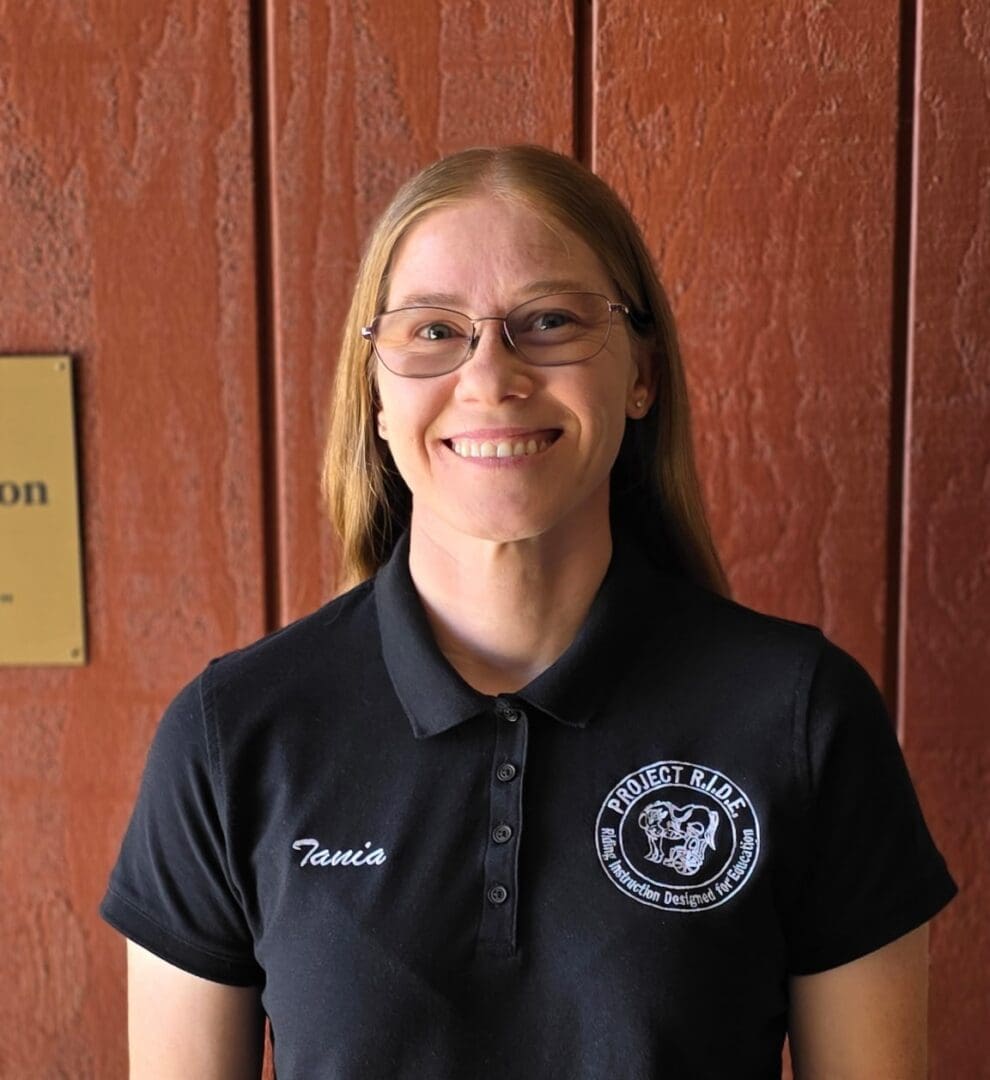 Smiling woman in black polo, wood background